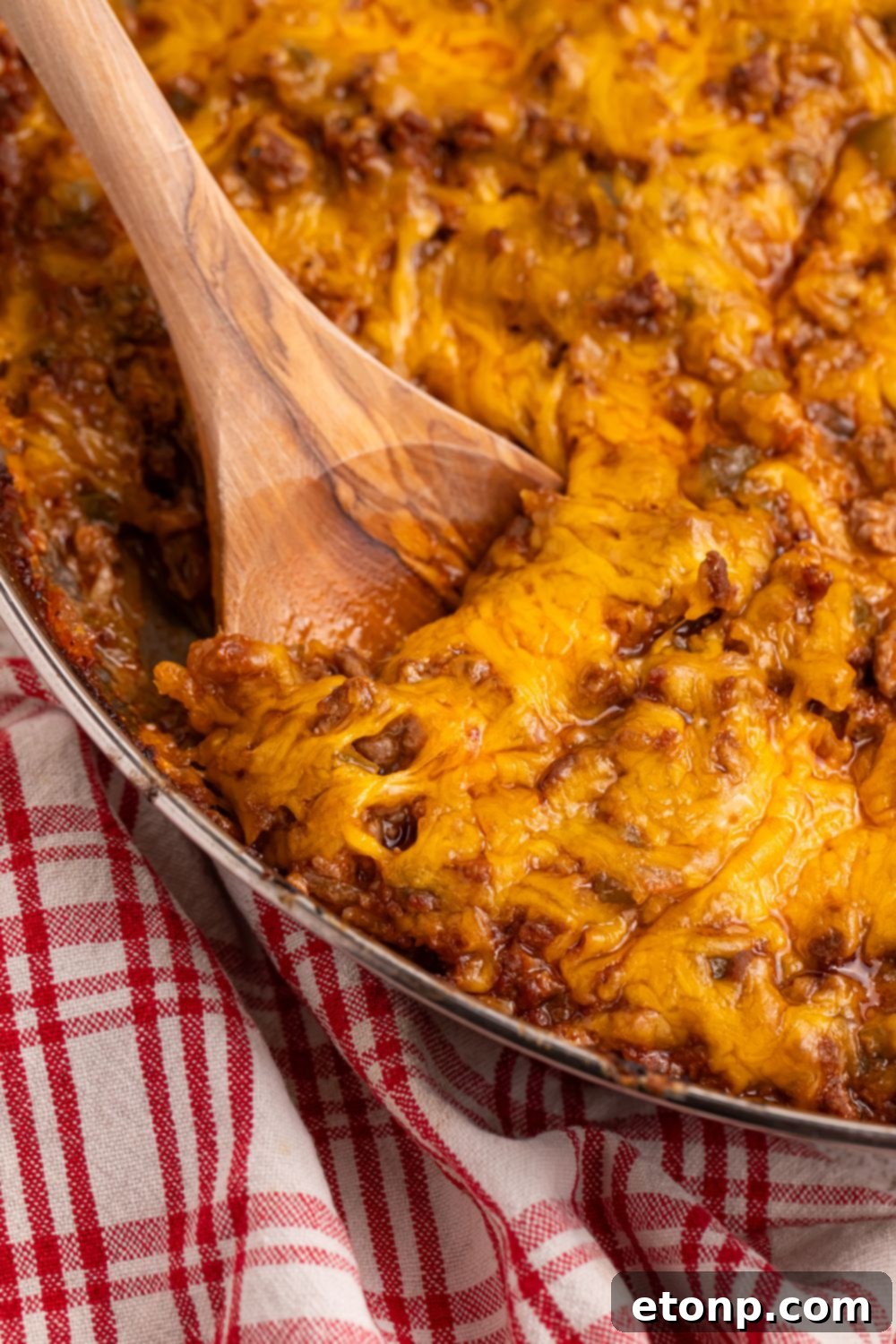 Ultimate Sloppy Joe Dip 6 A wooden spoon scooping a portion of rich Sloppy Joe Dip from a metal pan, highlighting its thick and hearty texture, perfect for sharing.