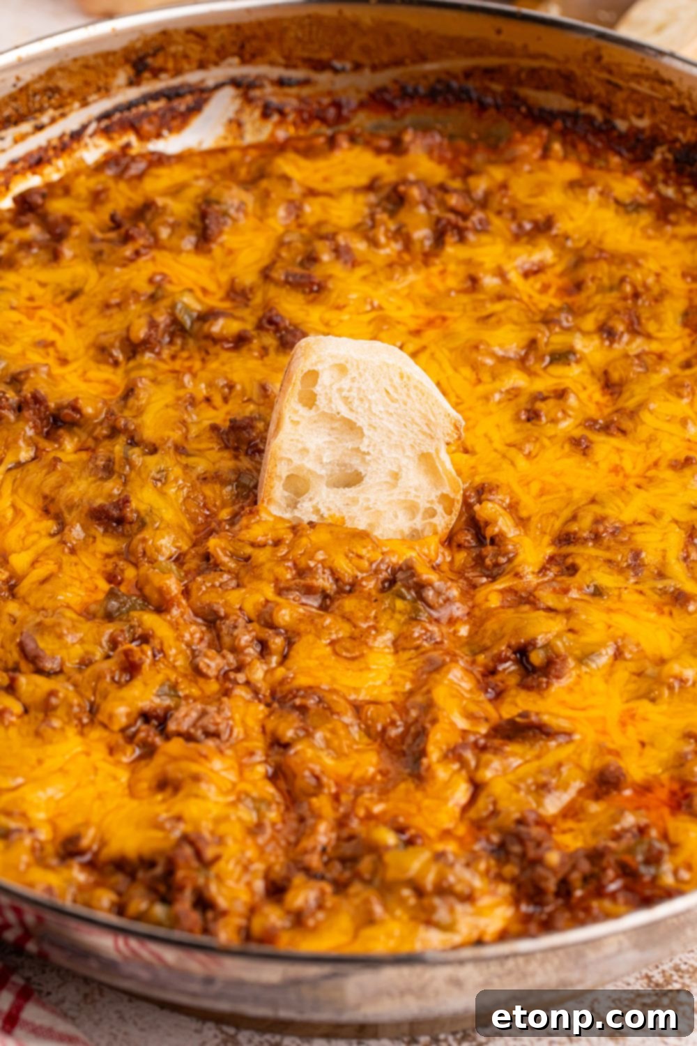 Ultimate Sloppy Joe Dip 8 A shimmering metal pan filled with hot Sloppy Joe Dip, with a slice of golden-brown bread nestled invitingly in the center, ready for dipping.