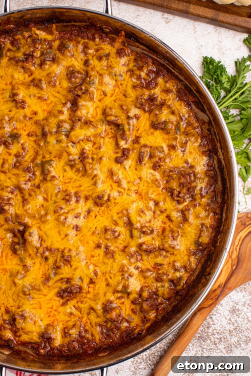 Ultimate Sloppy Joe Dip 9 A pan of Sloppy Joe Dip sits on a rustic surface, a wooden spoon resting on the side, inviting you to dig into its savory goodness.