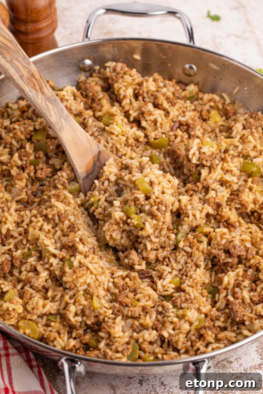 Cajun Dirty Rice 16 Dirty Rice in a pan with a spoon on the side of pan