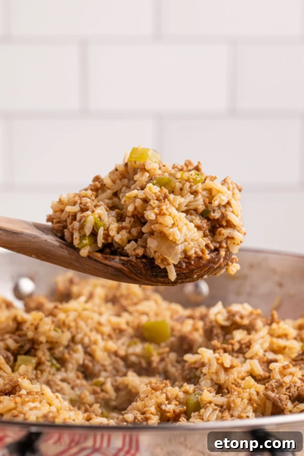 Cajun Dirty Rice 6 Dirty Rice in a pan with a wooden spoon of rice on it