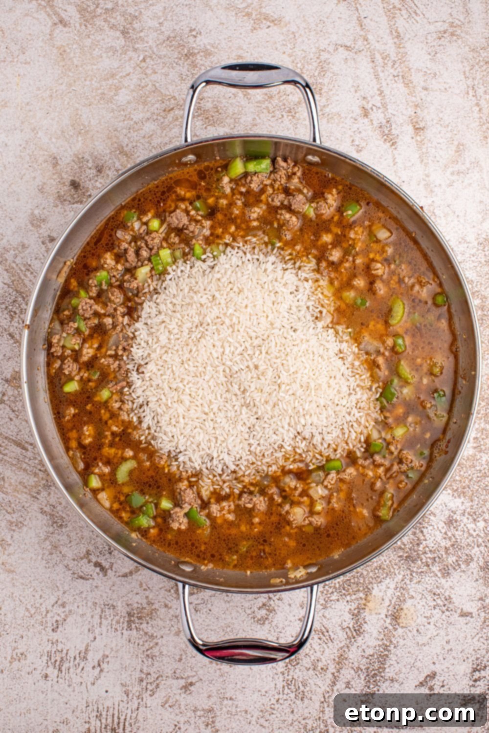 Cajun Dirty Rice 10 Dirty Rice - broth and rice added to meat mixture on table