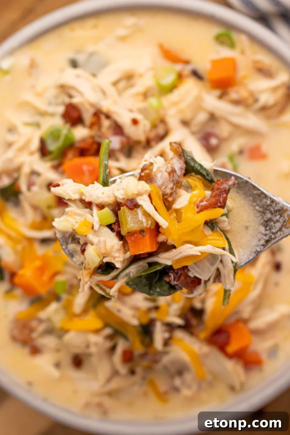 Creamy Ranch Chicken Soup 14 Crack Chicken Soup in a white bowl on table with a spoon of soup being held above the pan