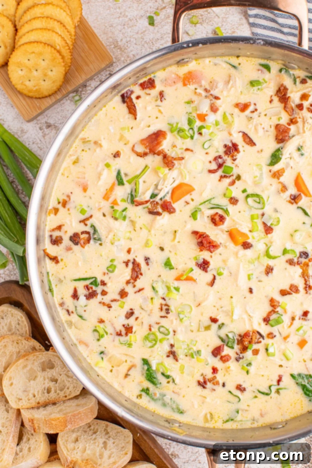 Creamy Ranch Chicken Soup 15 Crack Chicken Soup in a pan with crackers and sliced bread on the side