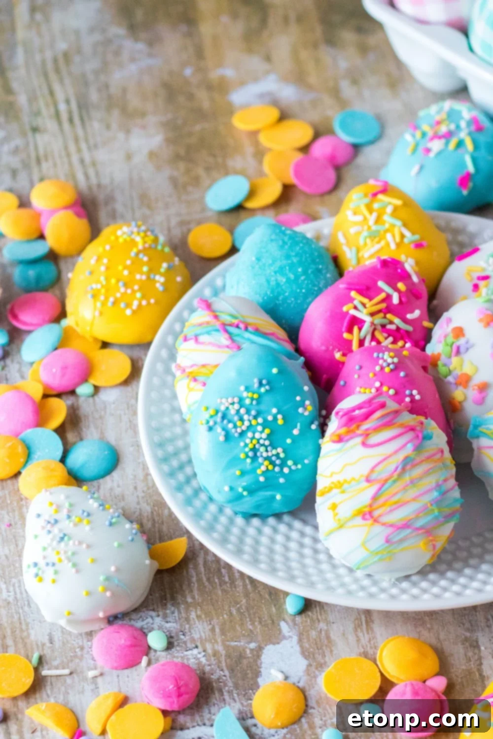 Easter Egg Oreo Truffles sat up on plate and a few scattered on a wooden table 