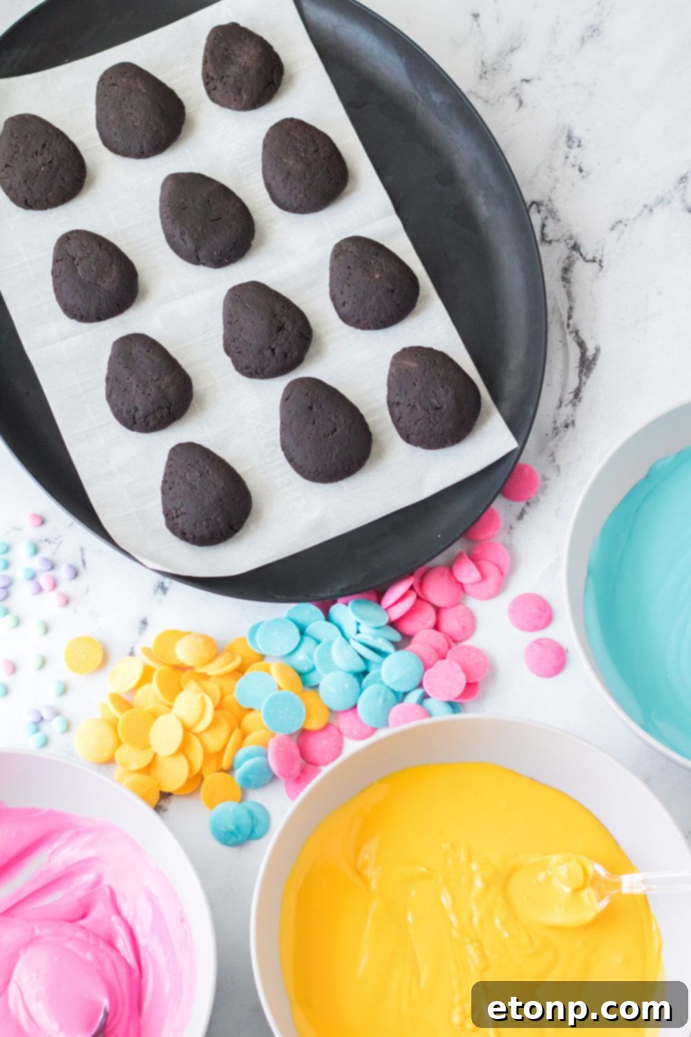 egg shaped Easter Egg Oreo Truffles on table with melted chocolates in bowls