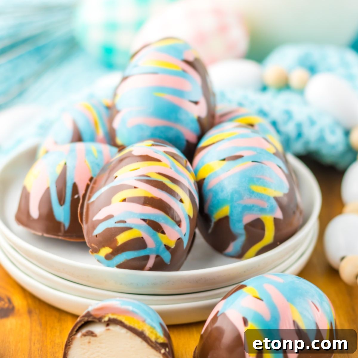 Easter Marshmallow Eggs on a plate on table wih an egg slice in half to show the marshmallow filling sitting on table 