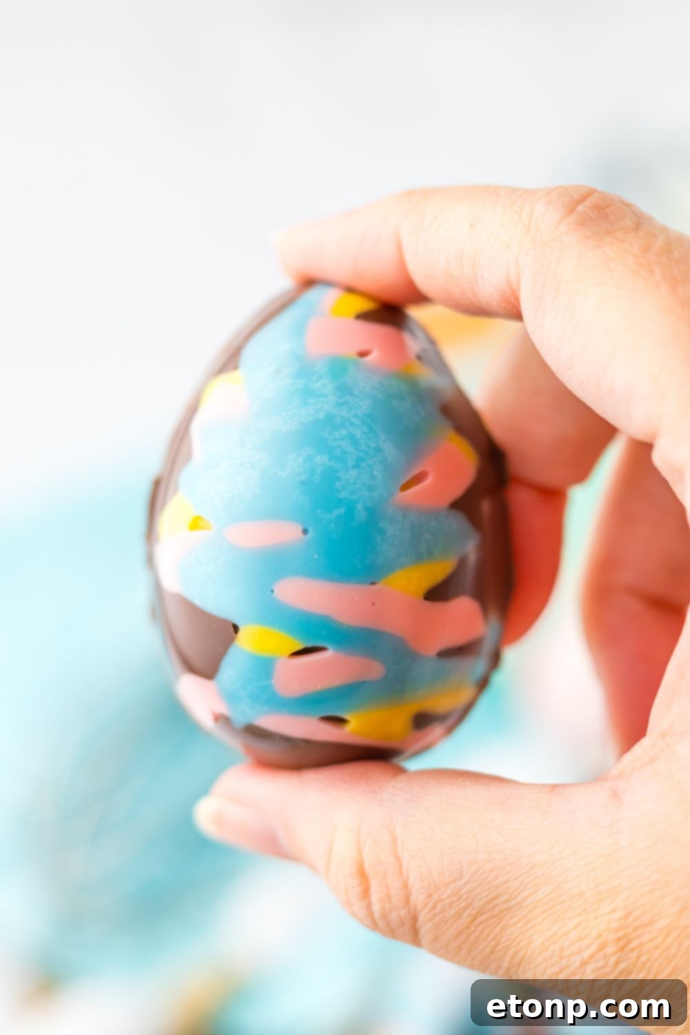 Easter Marshmallow Egg being held in a hand above the table 