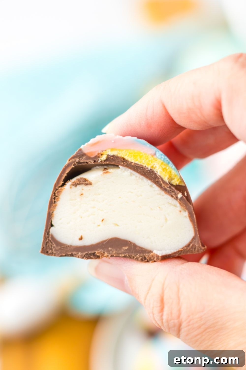 Easter Marshmallow Egg cut in half and showing the filling while being held in a hand 