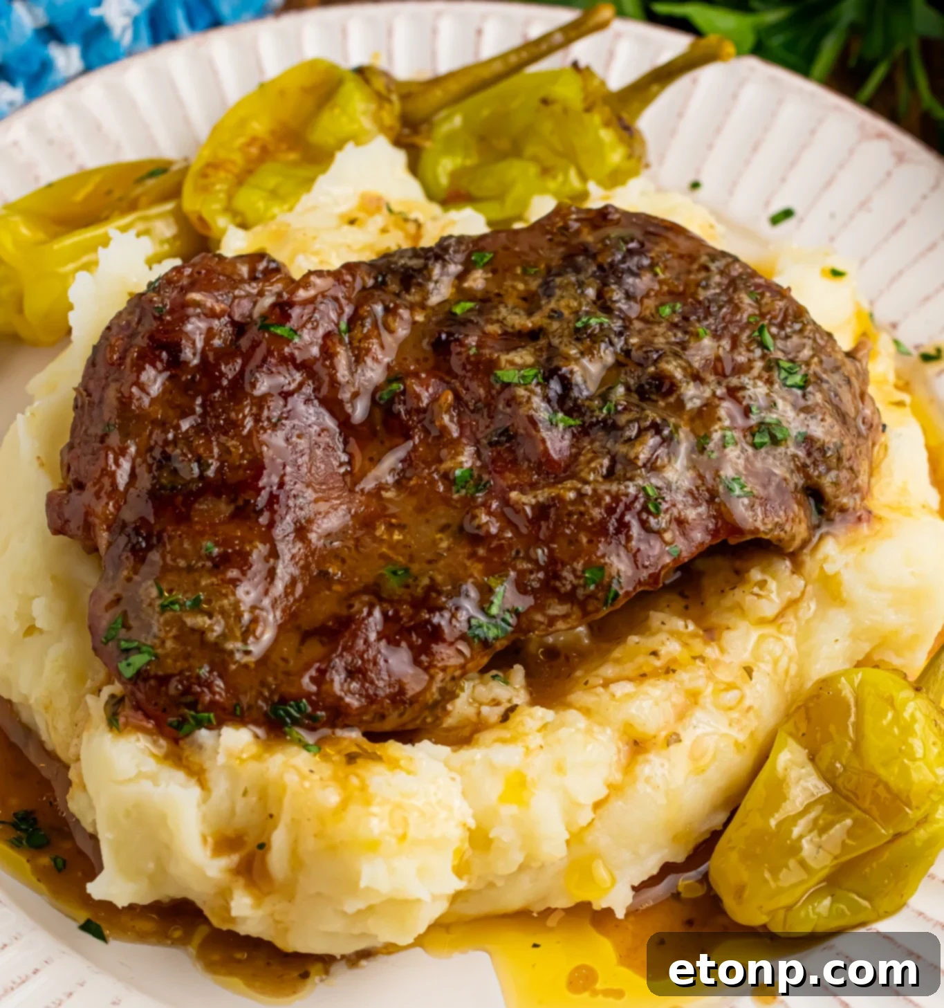 Up close shot of the Slow Cooker Mississippi Ribeye Steaks on a white plate, on top of fluffy mashed potatoes with gravy