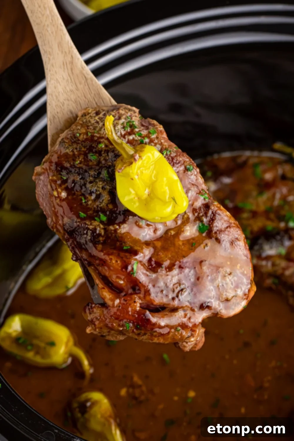 steak being lifted out of slow cooker with spoon - Slow Cooker Mississippi Ribeye Steaks
