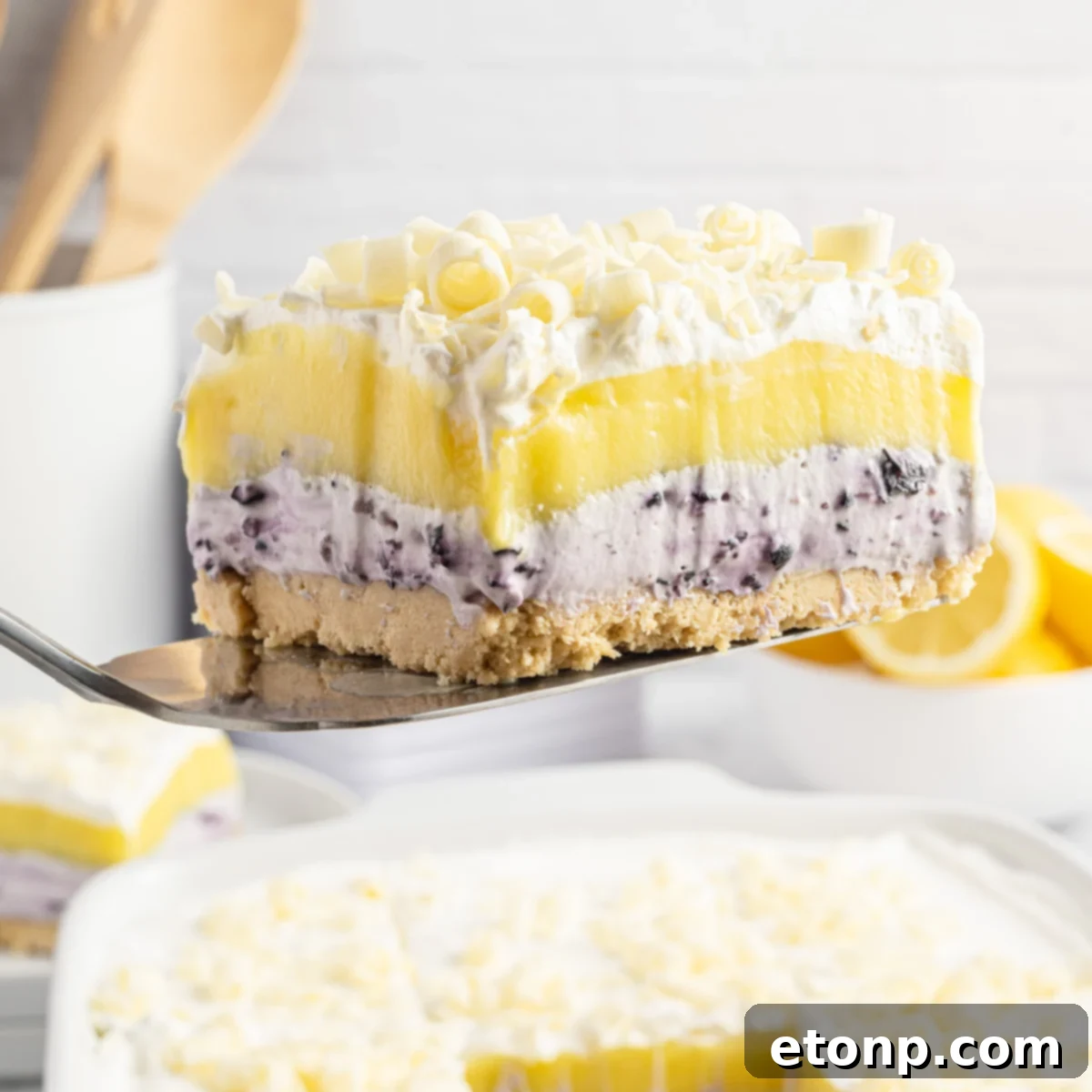 Lemon Blueberry Dream 2 piece of lemon blueberry lush being lifted out of a white baking pan