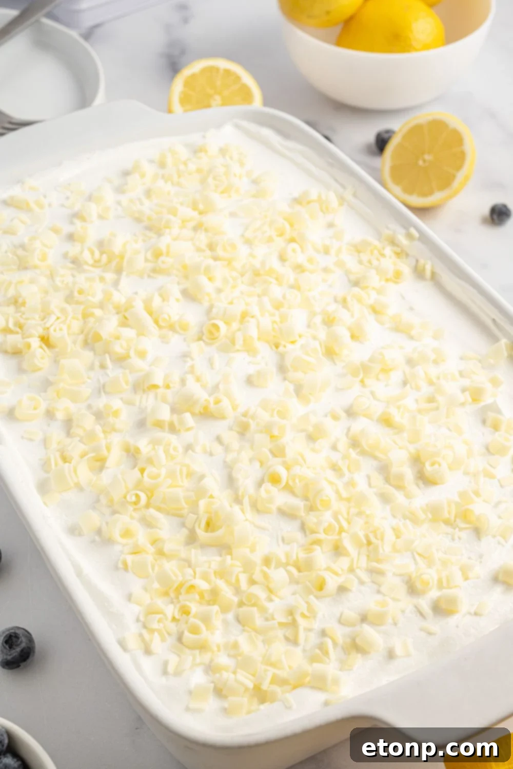 Lemon Blueberry Dream 13 white chocolate shavings sprinkld over the top of he Lemon Blueberry Lush sitting on table