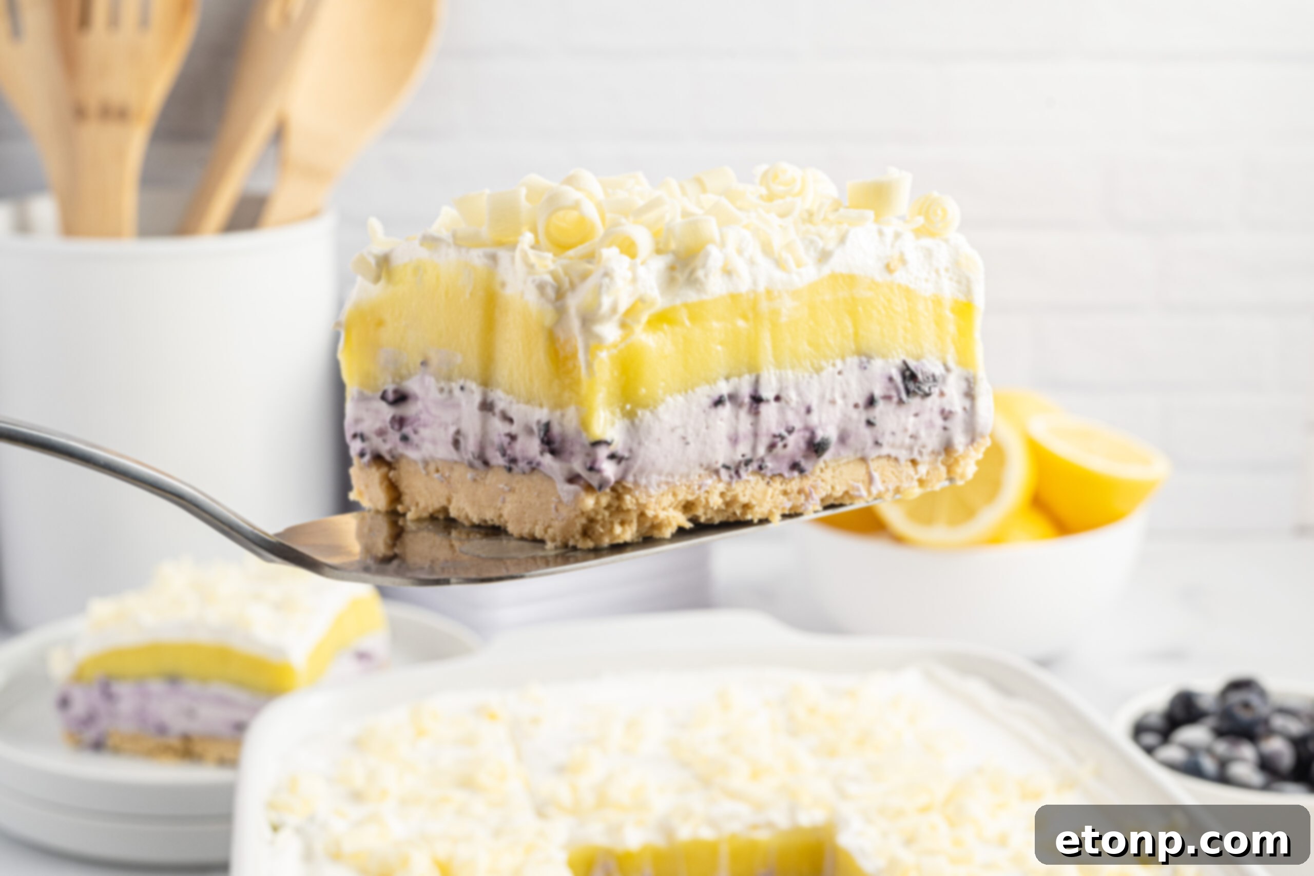 Lemon Blueberry Dream 23 piece of lemon blueberry lush being lifted out of a white baking pan