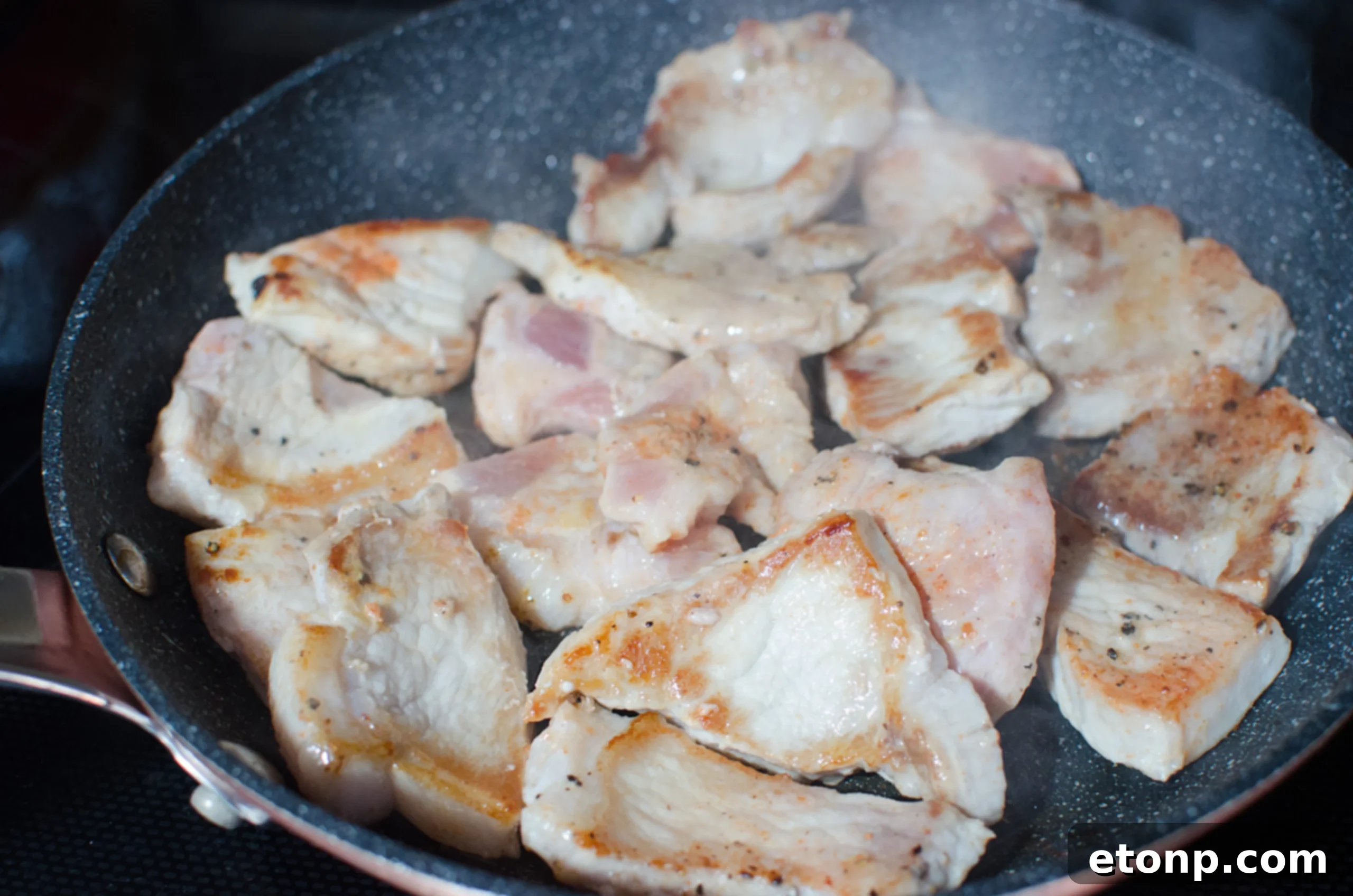 Close-up of seared pork pieces in a pan, ready for the slow cooker