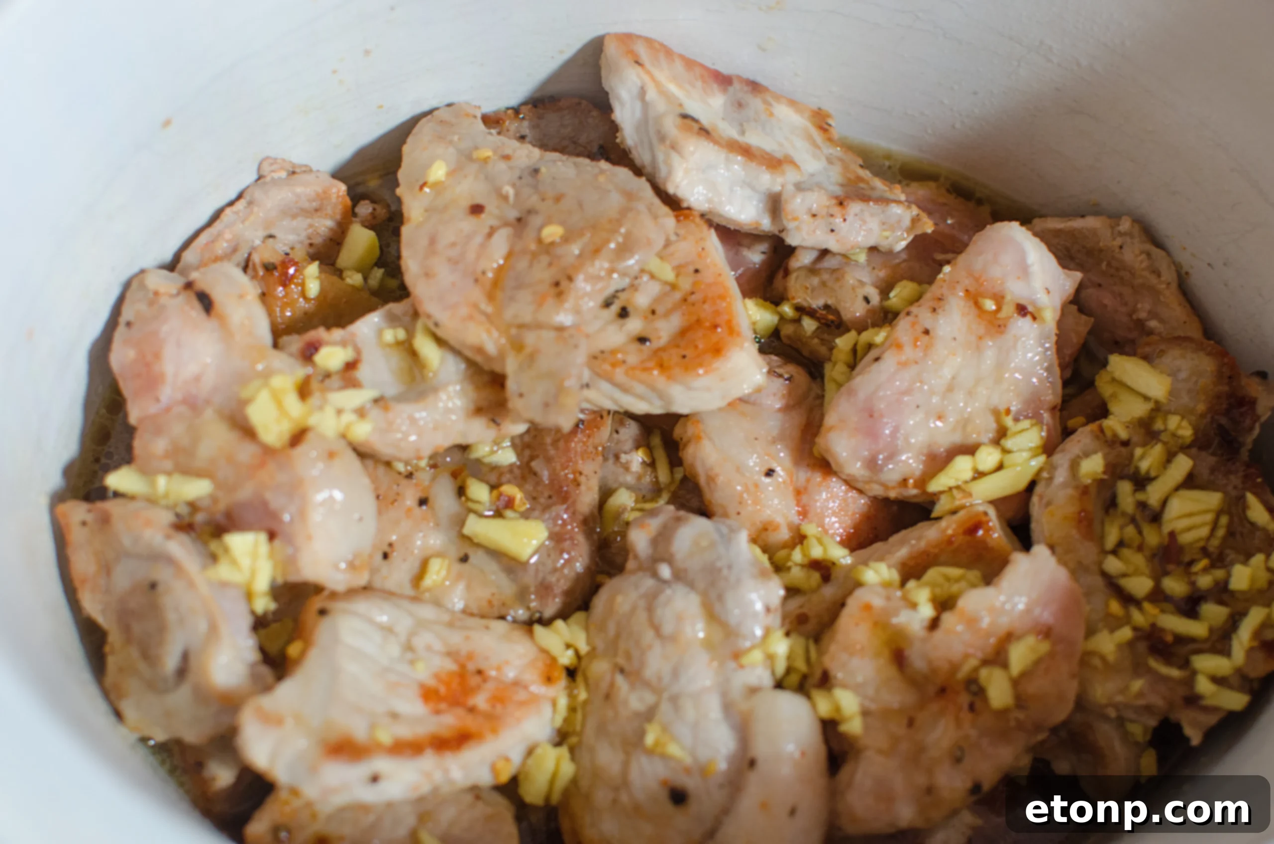 Caramelized pork pieces arranged in the slow cooker