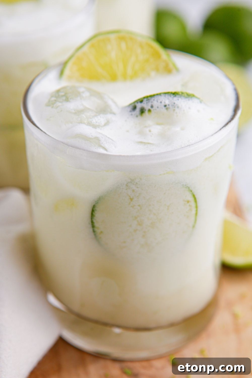 creamy limemade in glasses with limes and ice in it sitting on table 