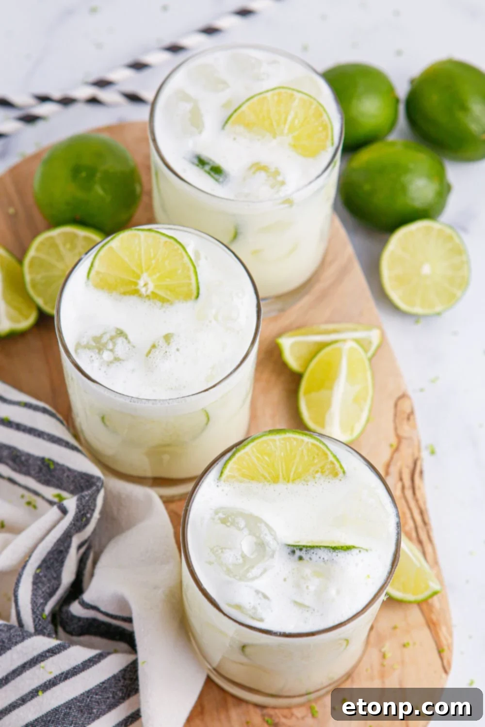 limeades in glasses on table with blue and white towel and limes placed around glasses