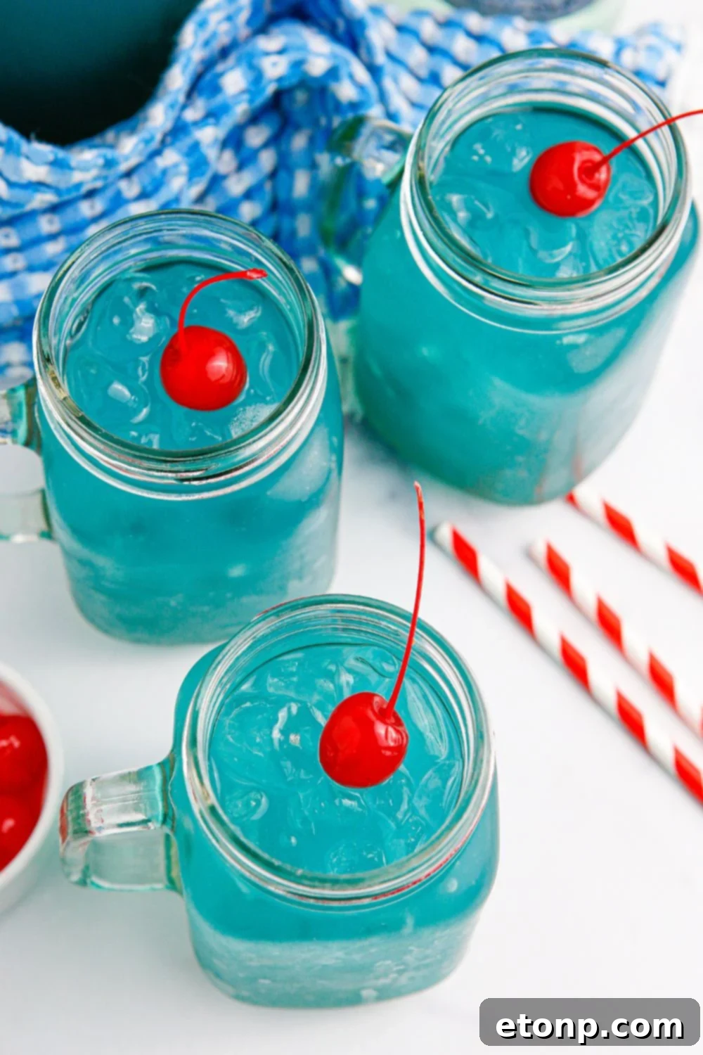 Blue drinks in glasses with a red cherry on top of each glass