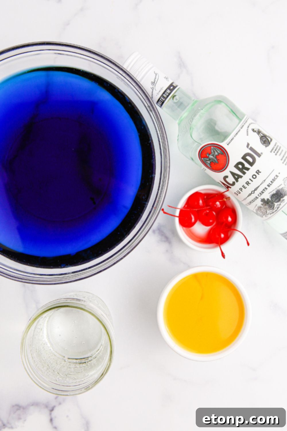 Hawaiian punch ingredients on marble counter including Kool-Aid, Sprite, pineapple juice, rum, and cherries