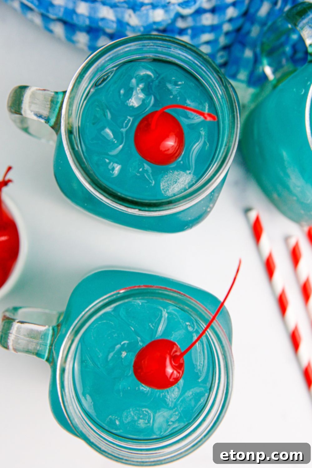 Blue Hawaiian Punch in mason jar glasses on table with straws around it