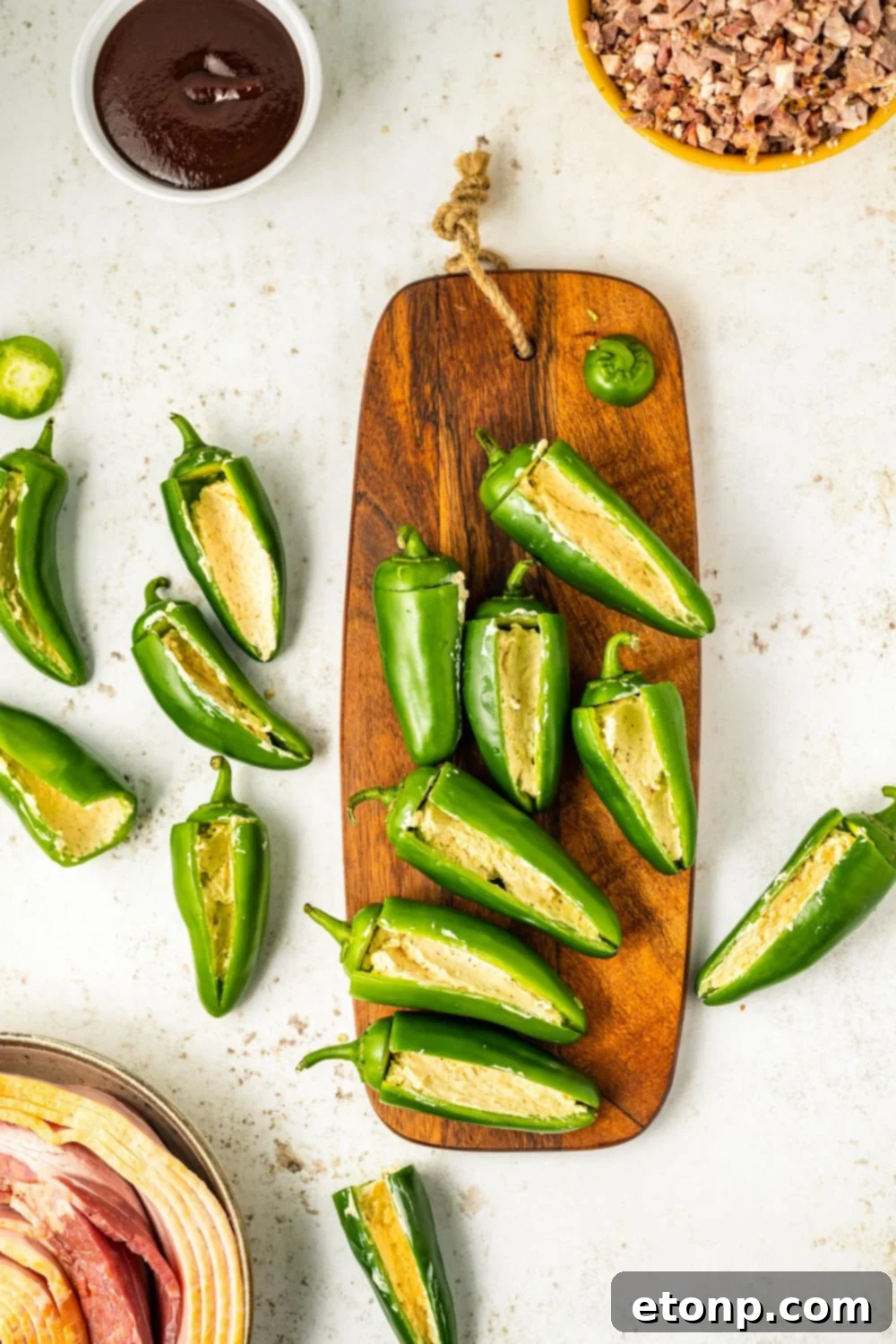 Fresh jalapeno peppers sliced lengthwise and placed on a wooden cutting board, ready for preparation