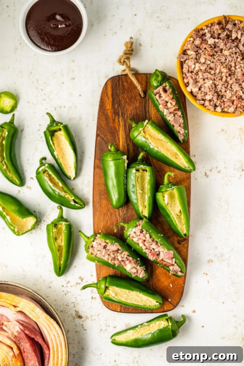 Jalapenos already stuffed with a creamy cream cheese and brisket mixture, resting on a cutting board