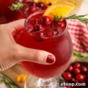 Cranberry Whiskey Sour cocktail in a glass being held in a lady's hand