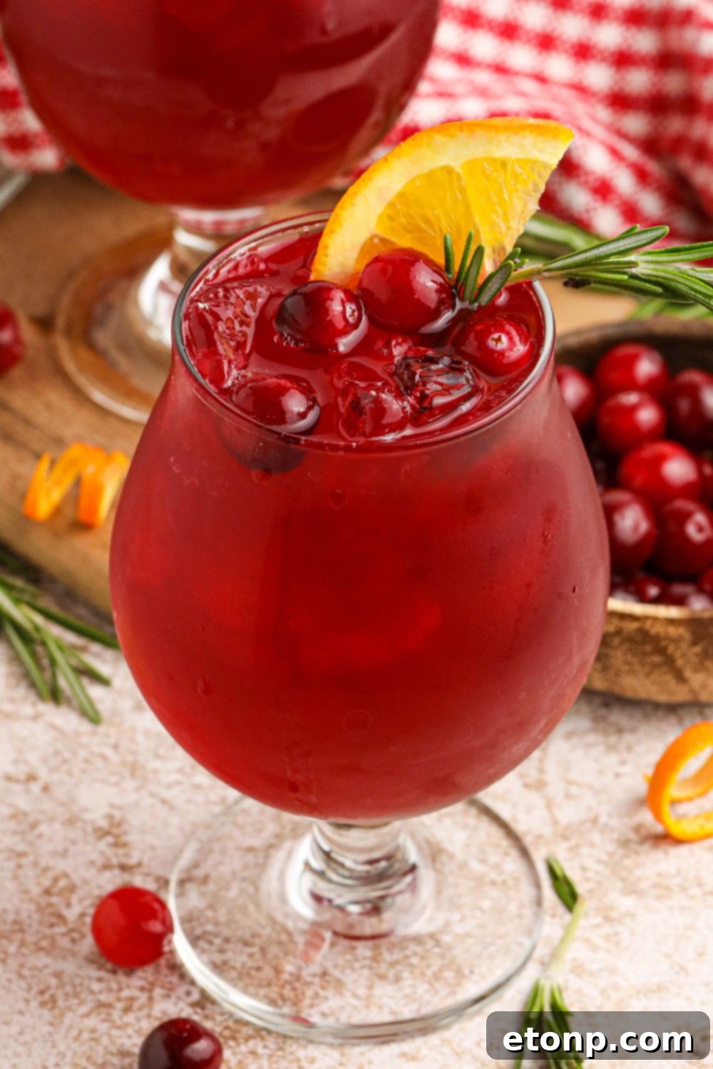 Cranberry Whiskey Sour in a cocktail glass garnished with cranberries, and an orange wedge on the glass, inviting and festive