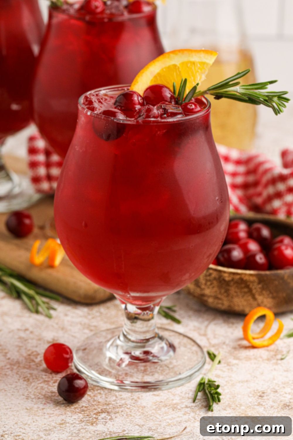 Cranberry Whiskey Sour cocktails on the table with cranberries and orange garnish