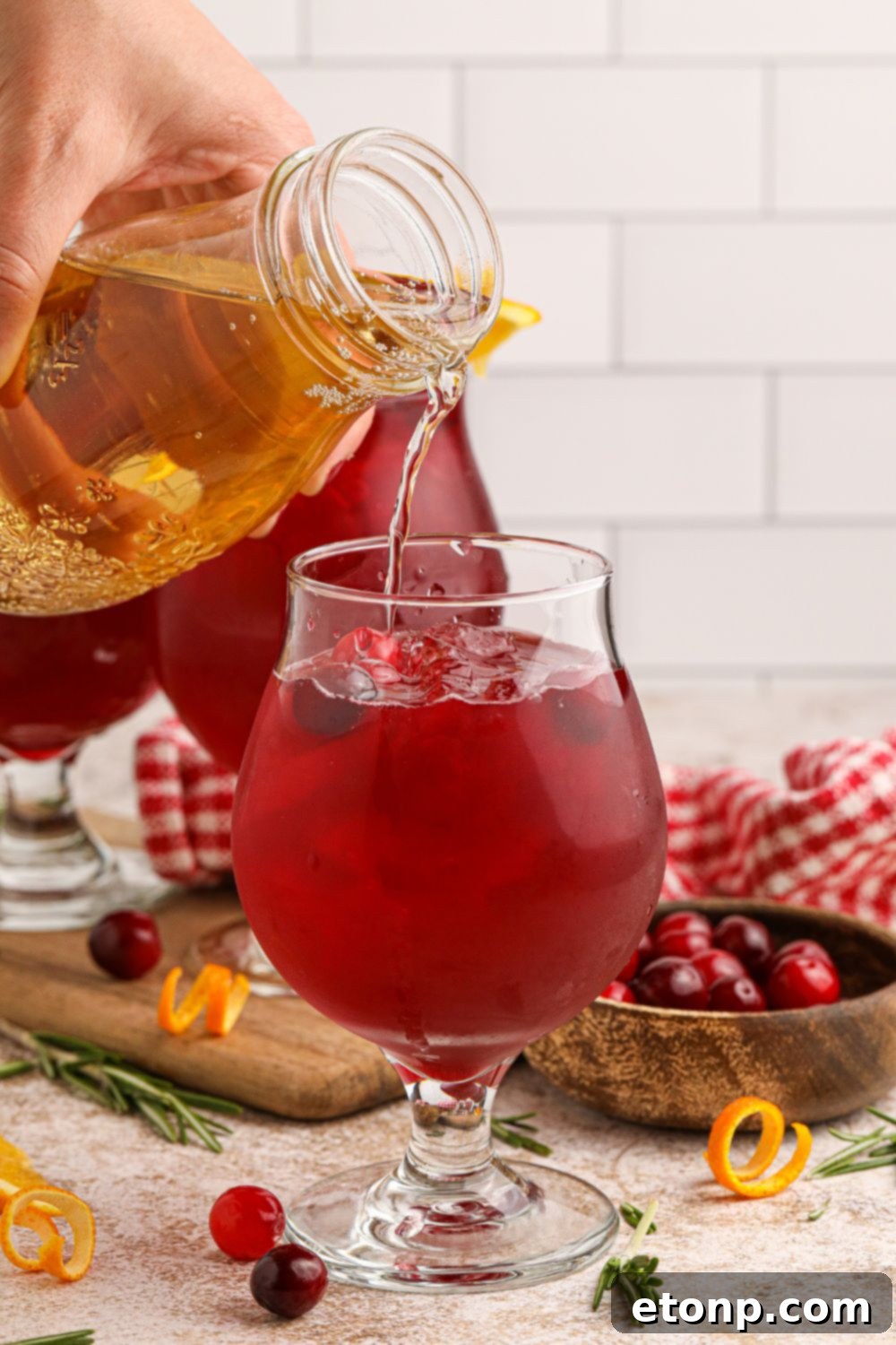 Pouring juice into a glass for making a cranberry cocktail, illustrating the mixing process