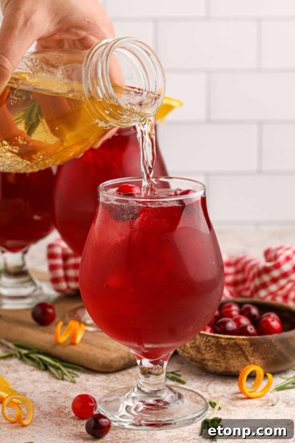 Cranberry Whiskey Sour on table with juice being poured into the glass to top it off