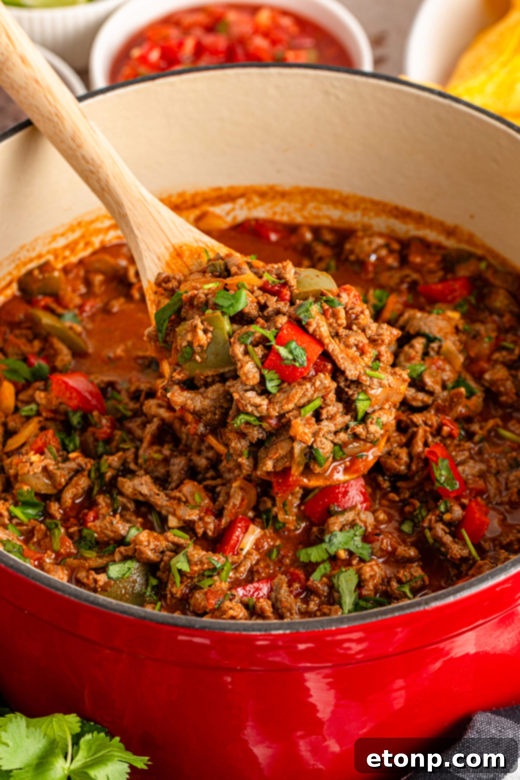 Ground Beef 2 Carne Picada in a dutch oven pot with a wooden spoon lifting up some to show texture