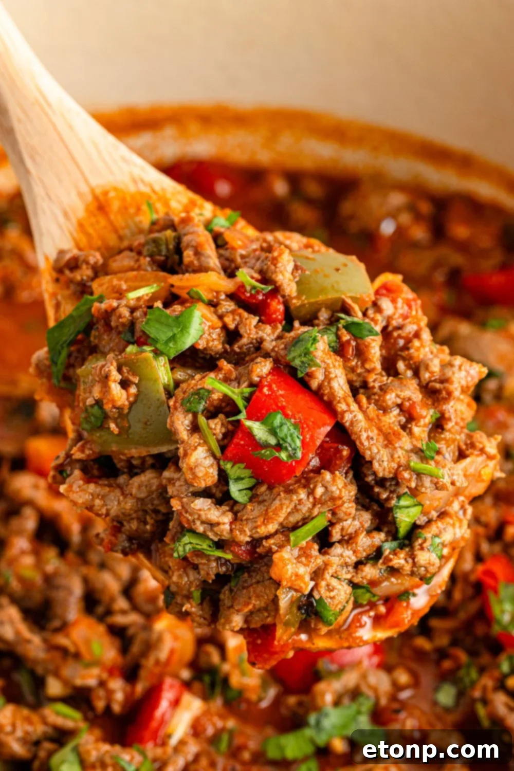 Ground Beef 14 wooden spoon over Dutch Oven with beef picada on the spoon