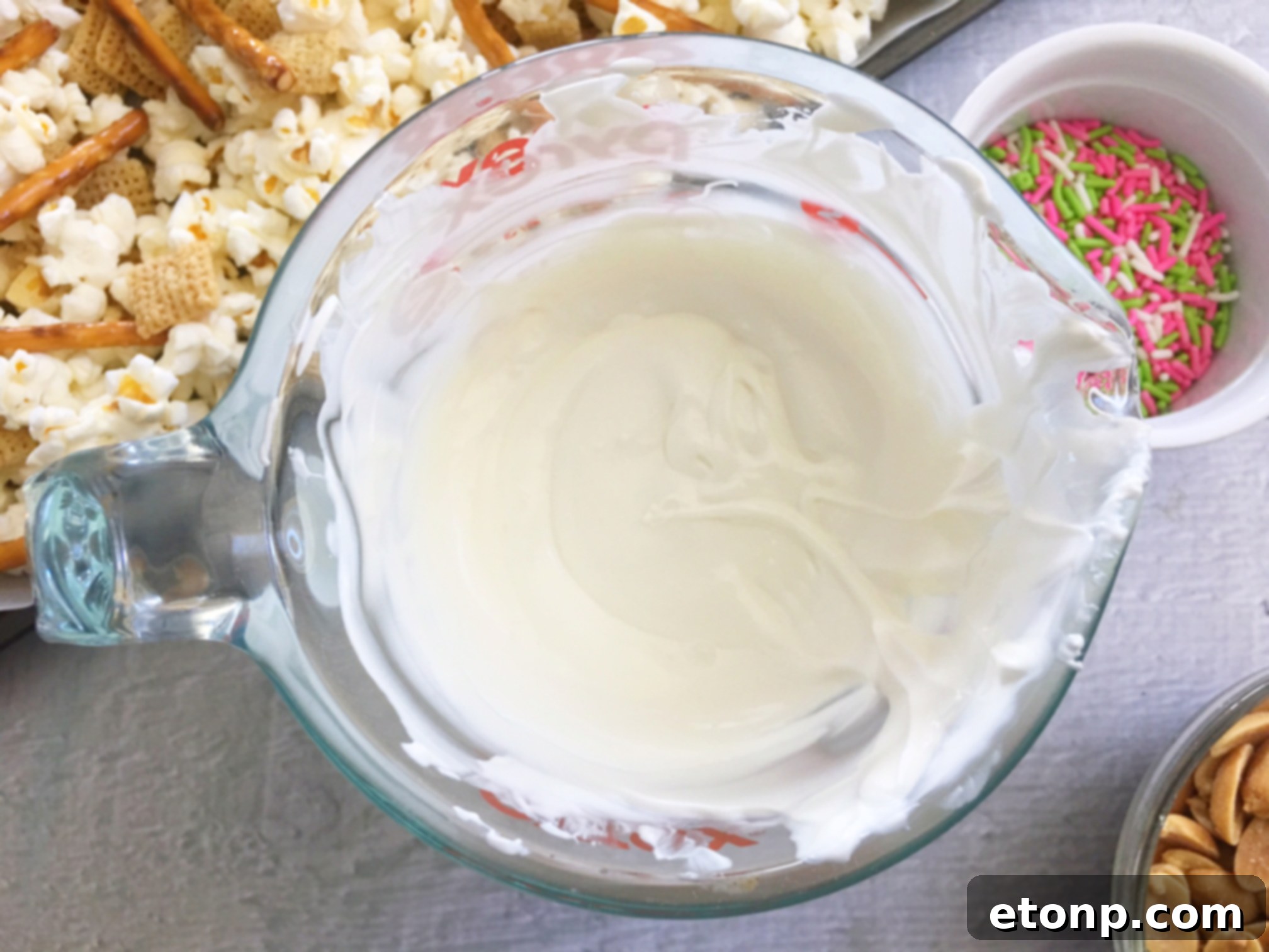A baking sheet filled with Bunny Bait snack mix, ready to harden, featuring various ingredients like popcorn, pretzels, and M&Ms.