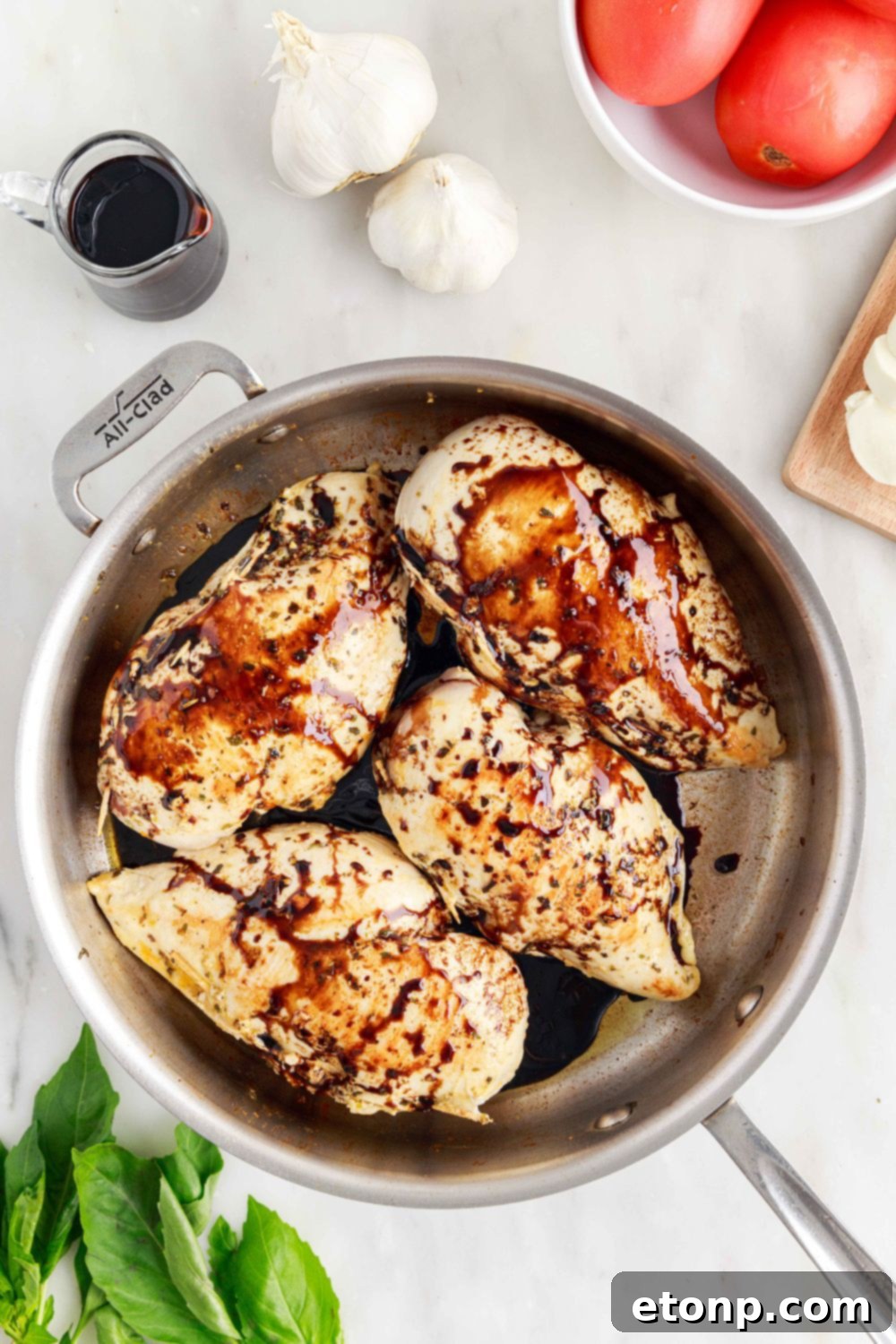 Balsamic glaze being poured generously on top of Caprese Stuffed Chicken in a pan