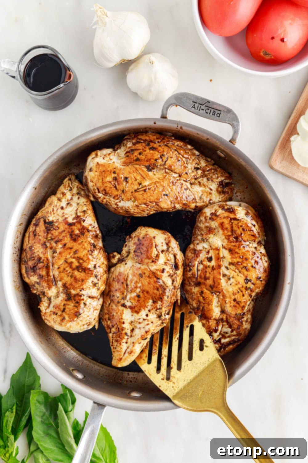 Caprese Stuffed Chicken in a pan being carefully flipped with a spatula to ensure even cooking