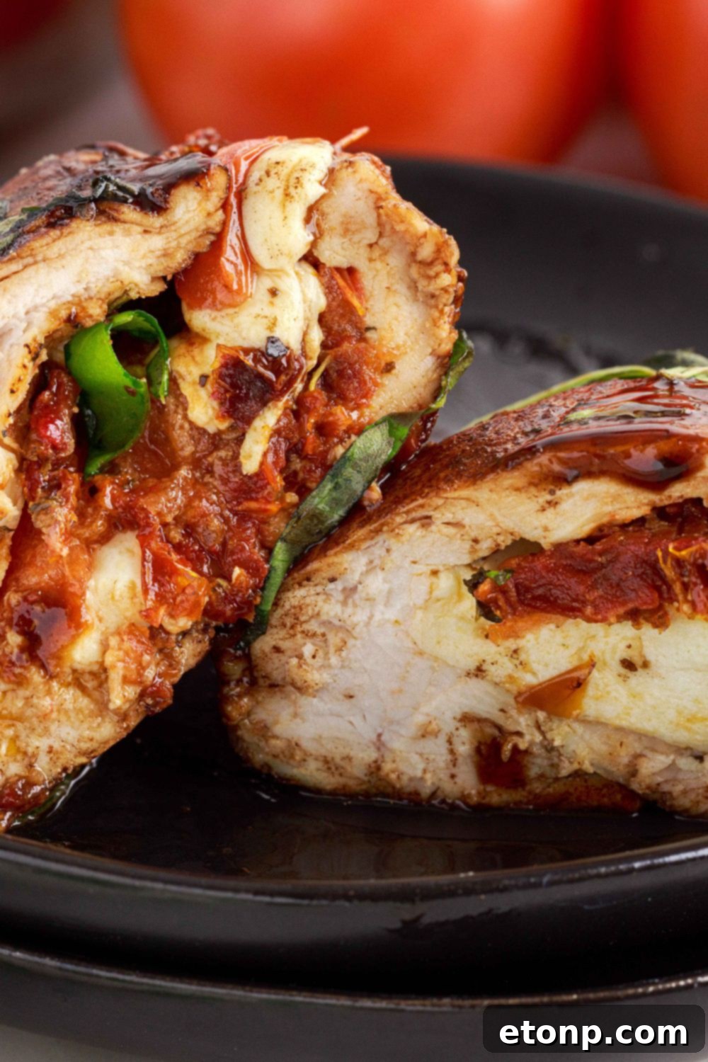 Caprese Stuffed Chicken cut in half and displayed on a plate to showcase the vibrant filling