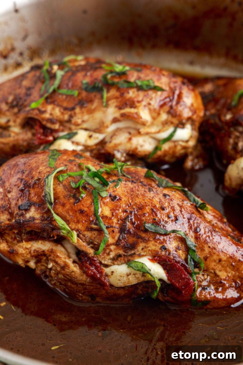 Side view of Caprese Stuffed Chicken sitting in a pan, highlighting its appealing presentation