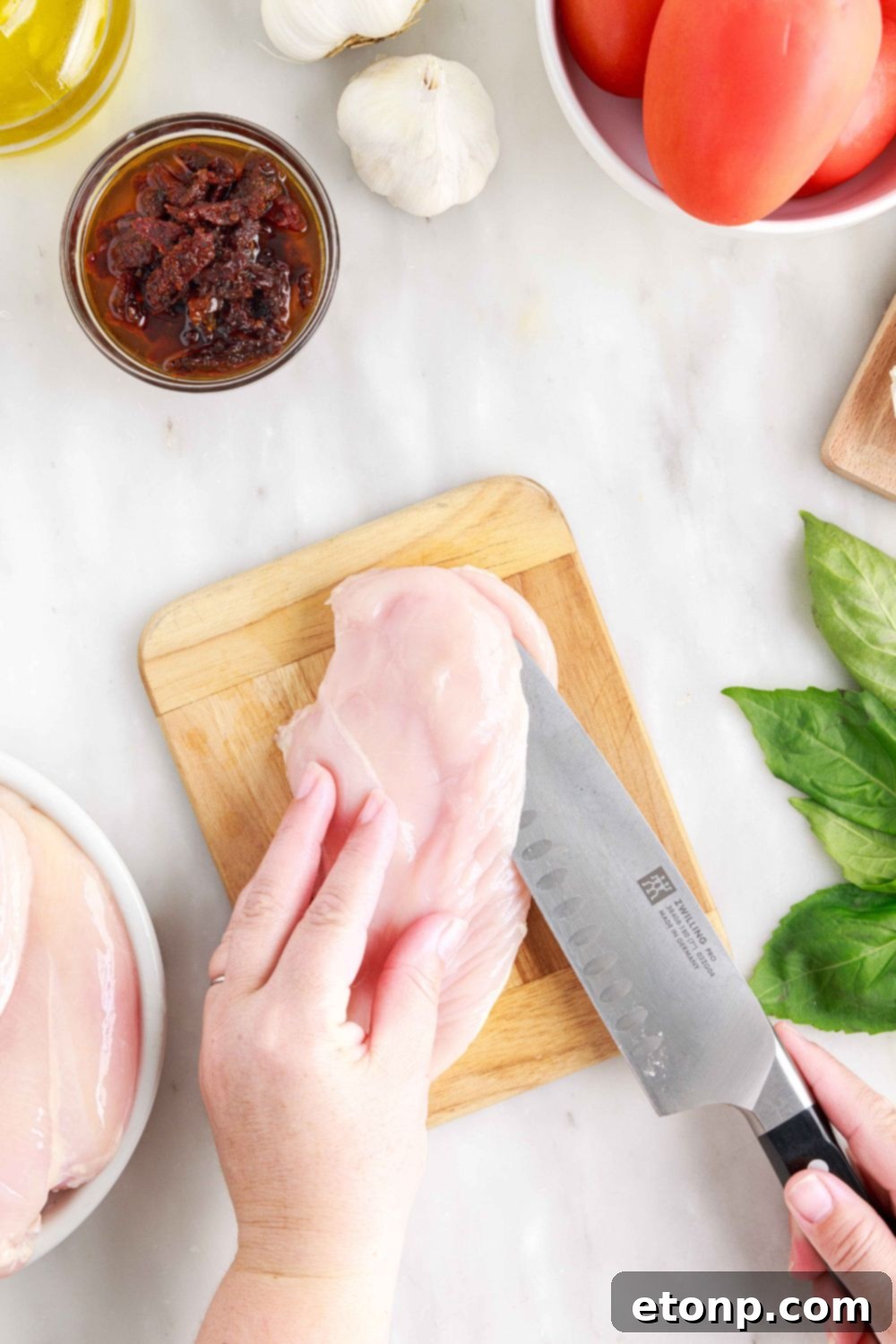 Raw chicken on a cutting board being butterflied