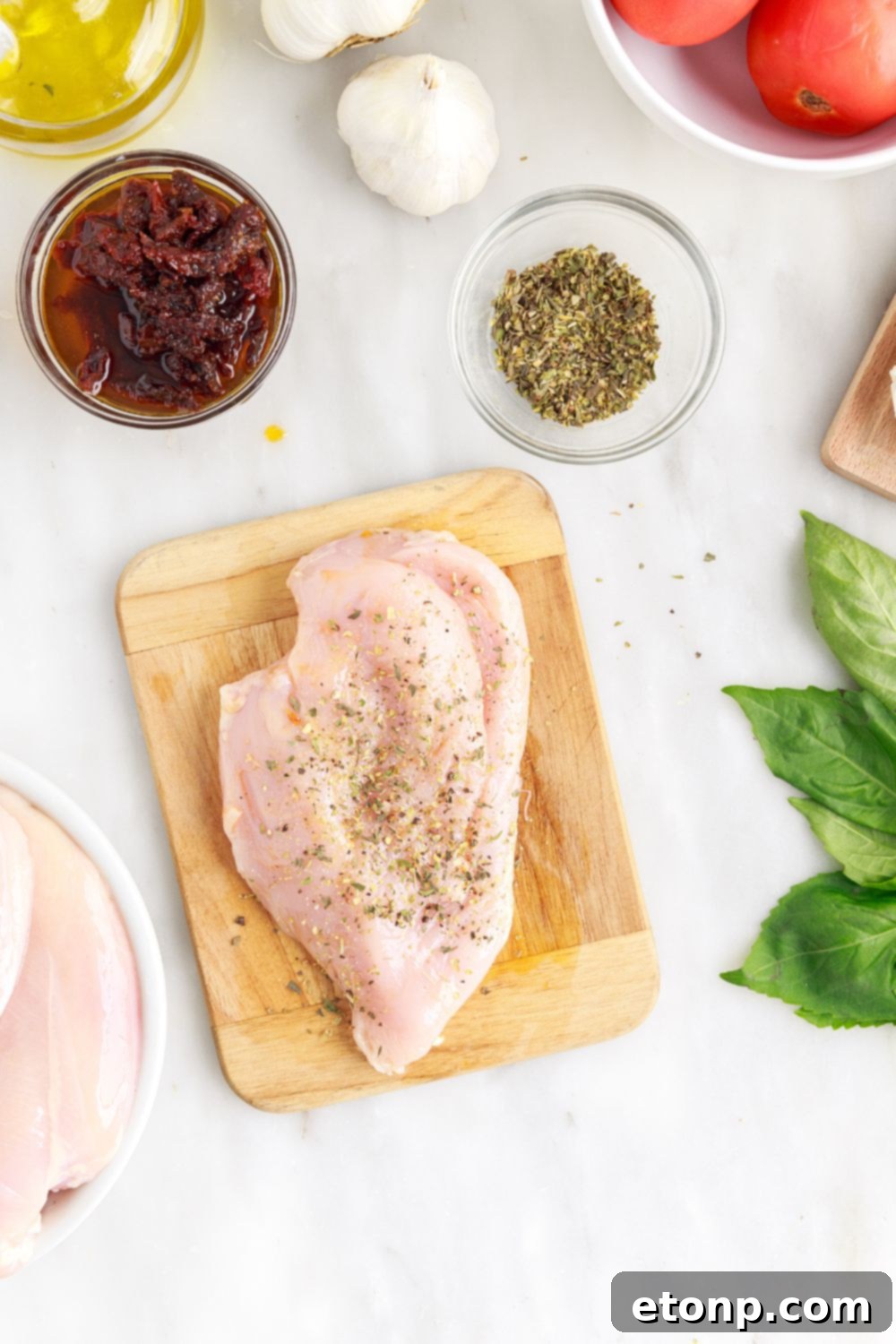 Seasoned raw chicken breast on a cutting board, ready for stuffing