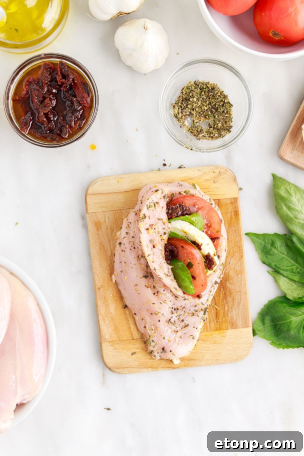 Stuffed raw chicken breast on a cutting board, secured with toothpicks for the Caprese Stuffed Chicken recipe