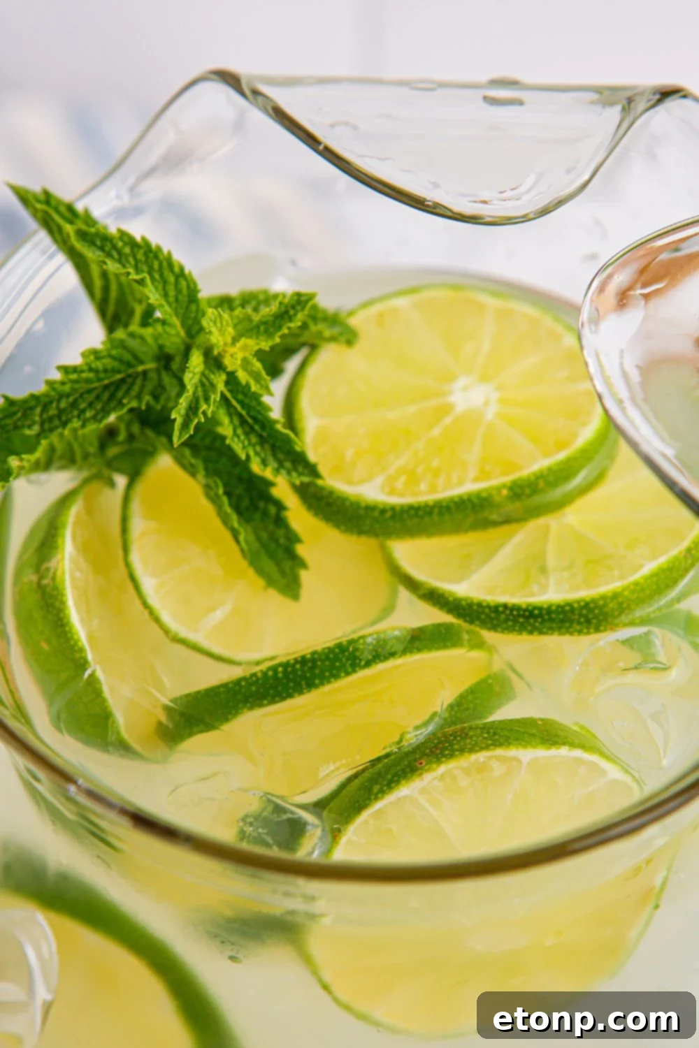 lime aid drink in a pitcher with mint and lime slices