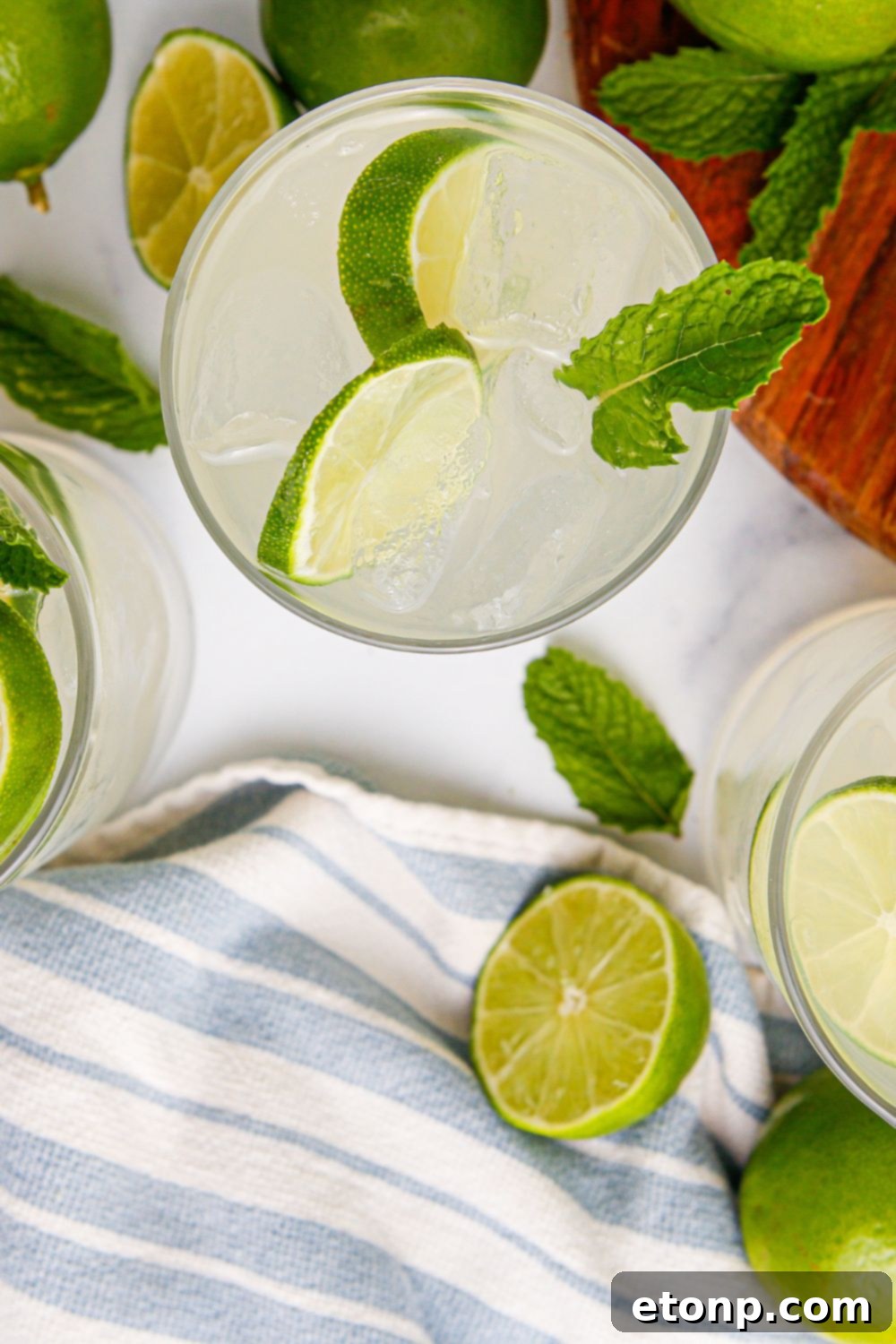 Limeade in glasses on table with a blue and white stripe on it sitting on table 