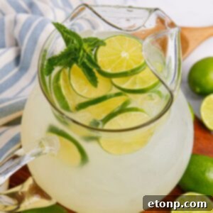 Limeade in a pitcher topped with sliced limes and mint leaves