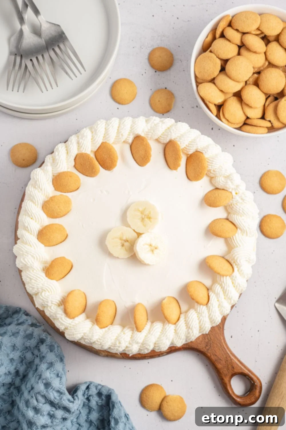 Dreamy No Bake Banana Pudding Cheesecake 12 Finished No-Bake Banana Pudding Cheesecake on a table, garnished with wafer cookies and fresh bananas.