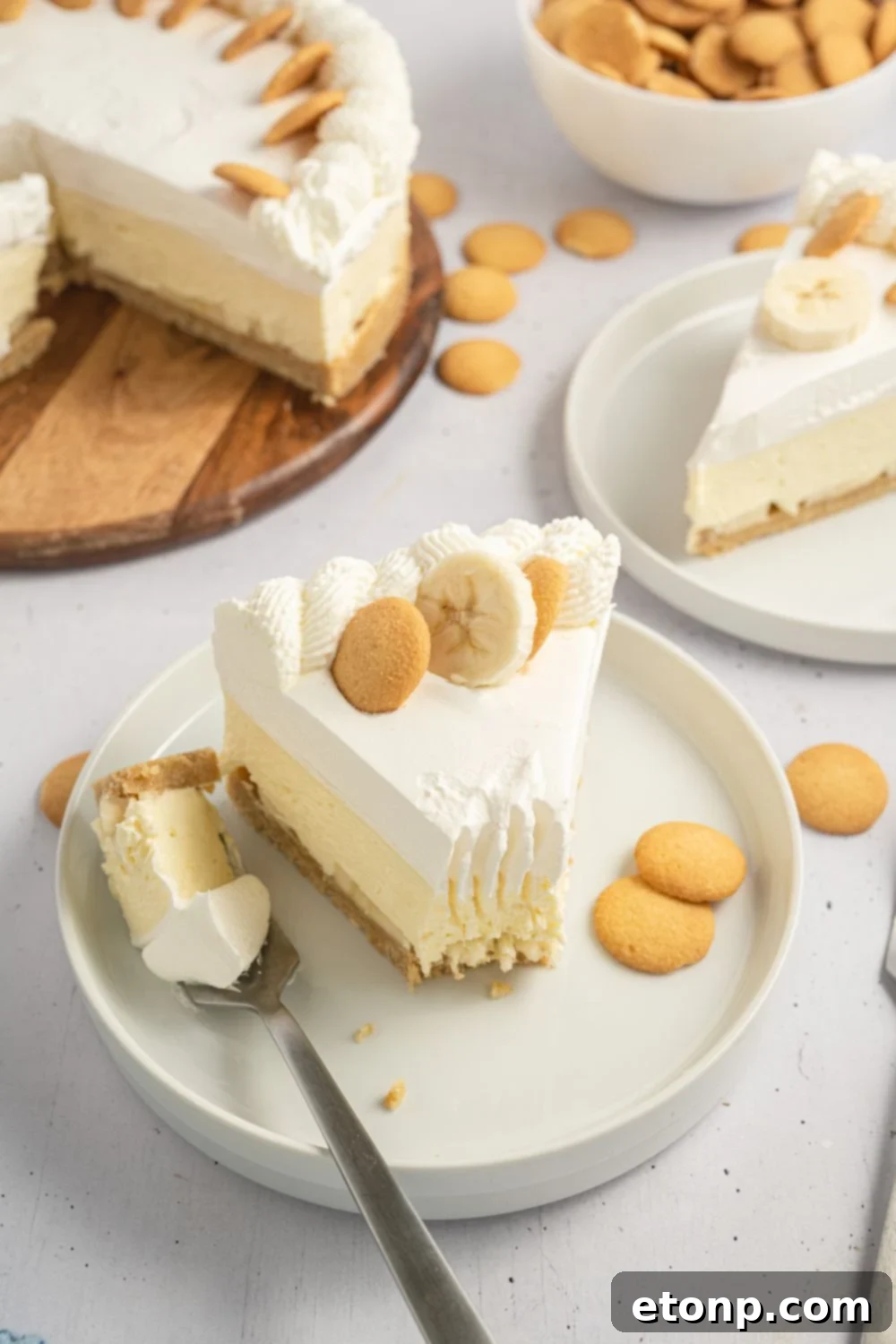 Dreamy No Bake Banana Pudding Cheesecake 20 Multiple slices of No-Bake Banana Pudding Cheesecake on white plates, with the whole cheesecake in the background.