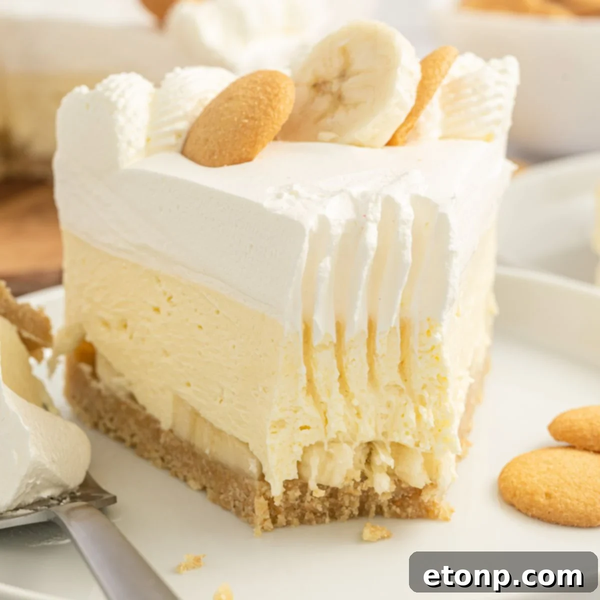 Dreamy No Bake Banana Pudding Cheesecake 3 A slice of No-Bake Banana Pudding Cheesecake on a plate with a fork taking a bite, showing the creamy layers.
