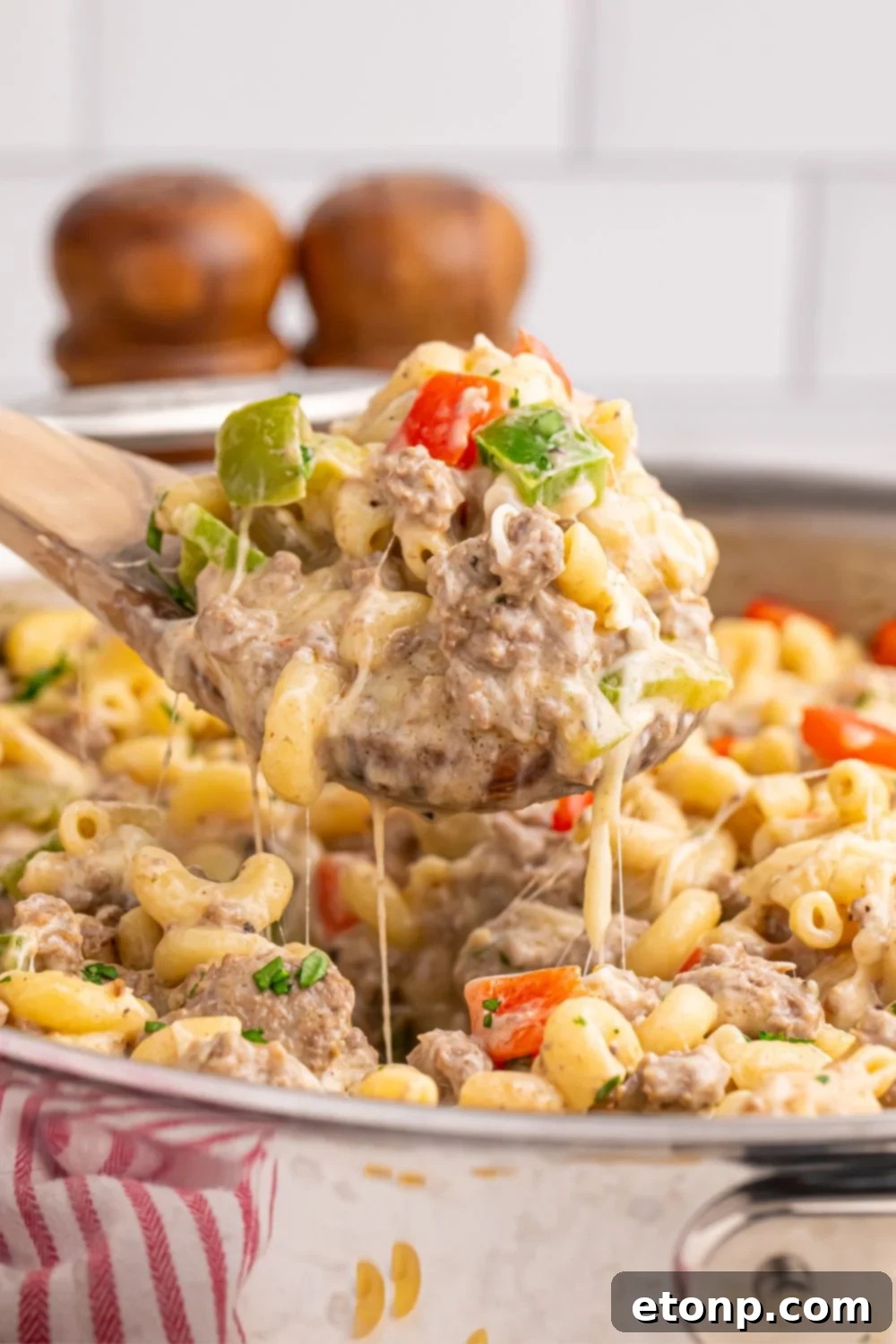 Philly Cheesesteak Pasta in skillet with a spatula scooping some pasta up with some strings of cheese