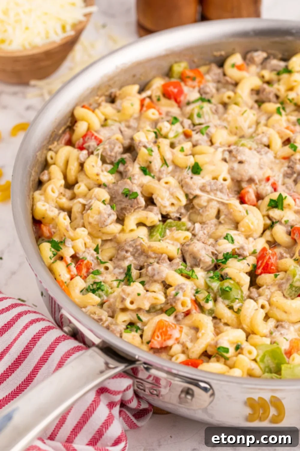 Philly Cheesesteak Pasta in a pan with a red striped towel on table by it 